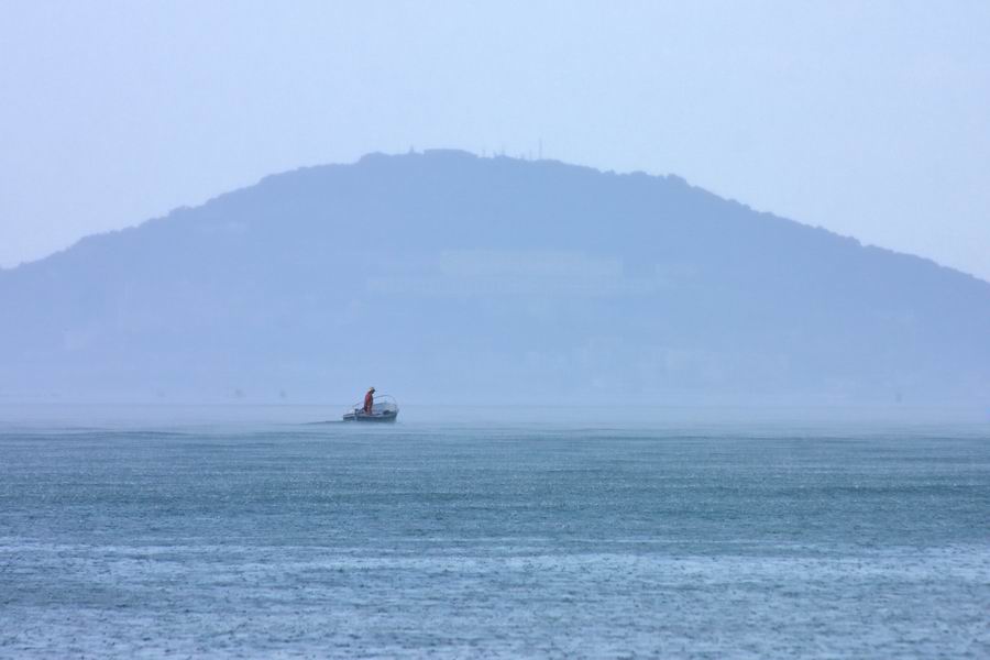 Одинокий рыбак в море, в дождь